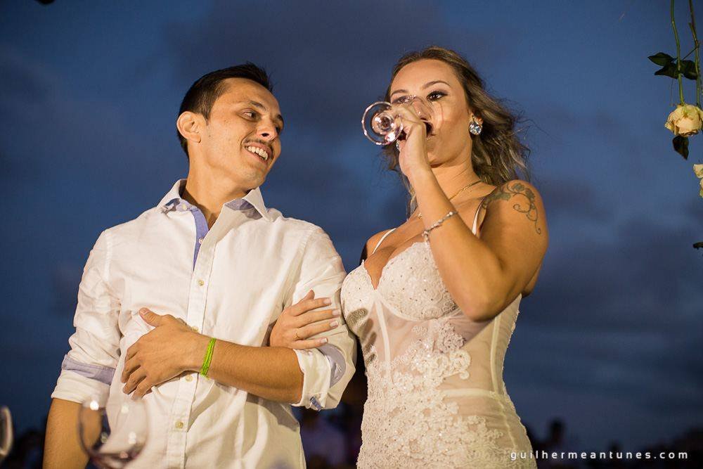 Foto de Casamento na praia de Larissa e Ronaldo noiva bebendo o brinde de tradição